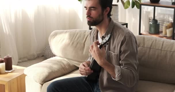 Hombre cantando canción y tocando la guitarra en casa — Vídeo de stock