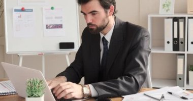 Ofiste dizüstü bilgisayarda çalışan iş adamı.