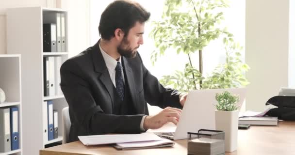 Geschäftsmann analysiert Dokument und arbeitet am Büro-Laptop — Stockvideo