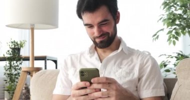 Evde cep telefonu kullanan adam.