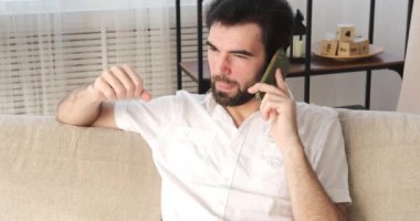 Evde cep telefonuyla konuşan adam.