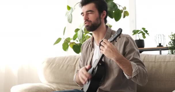 Чоловік співає пісню і грає на гітарі вдома — стокове відео
