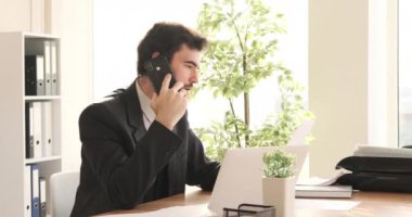 İş adamı ofiste çalışırken telefonda konuşuyor.