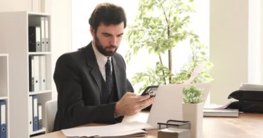 İş adamı ofiste çalışırken telefonda konuşuyor.