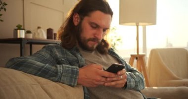 Evde cep telefonu kullanan adam.