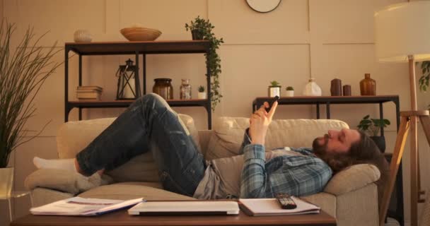 Frustrierter Mann schreibt SMS auf Handy zu Hause — Stockvideo