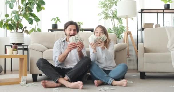 Förbluffade par kastar kontanter dollar i luften — Stockvideo