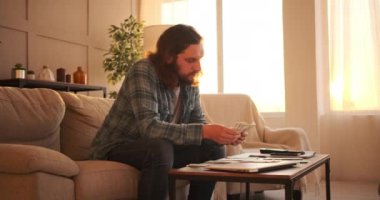 Düşünceli adam evde para sayıyor.