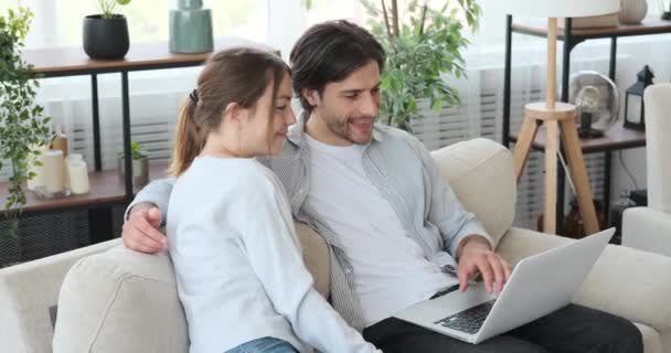 Casal feliz compras on-line usando laptop no sofá em casa — Vídeo de Stock