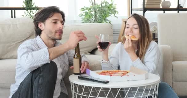 Çift evde televizyon izlerken yemek ve içkinin keyfini çıkarıyor. — Stok video