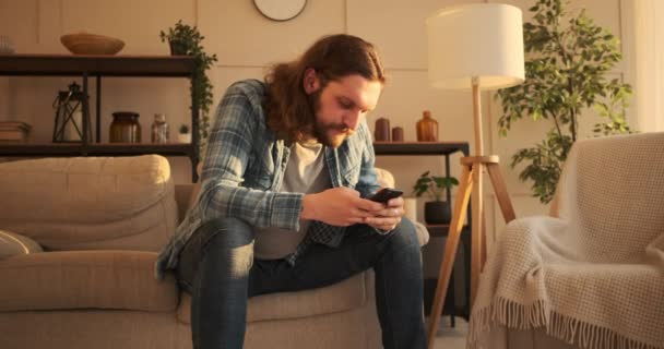 Mensajería de texto del hombre en el teléfono móvil en casa — Vídeo de stock