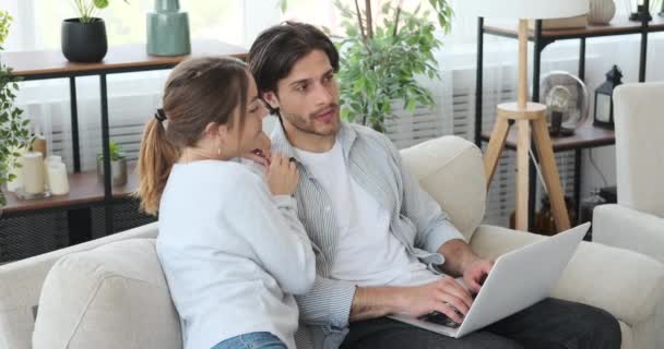 Glada par online shopping med laptop på soffan hemma — Stockvideo