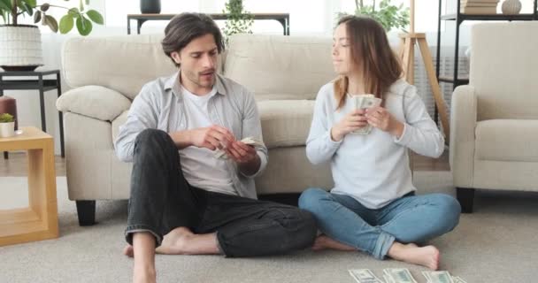 Mujer divertida contando y arrebatando billetes de dólar de marido para gastos futuros — Vídeos de Stock