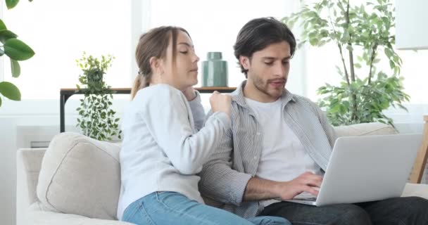 Un par de compras en línea utilizando el ordenador portátil en el sofá en casa — Vídeos de Stock