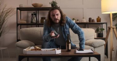 Pizzayı ve birayı seven bir adam evde televizyon izliyor.