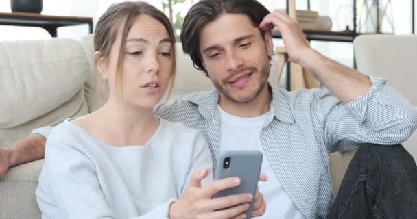 Překvapený pár pomocí mobilního telefonu doma — Stock video