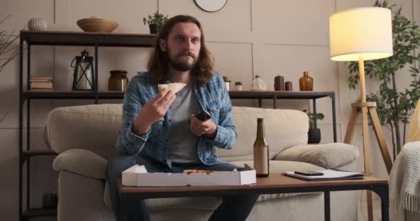 Hombre disfrutando de pizza y cerveza viendo la televisión en casa — Vídeo de stock