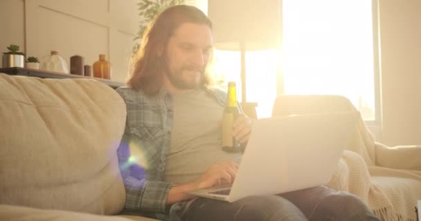 Man die thuis laptop gebruikt en bier drinkt — Stockvideo