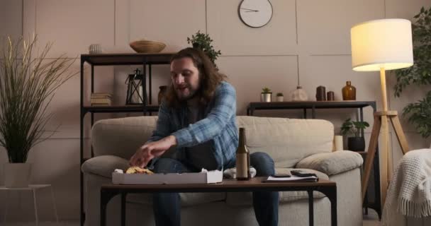 Чоловік насолоджується піцою та пивом, граючи у відеогру вдома — стокове відео