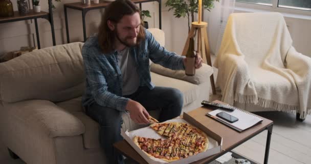 Pizzayı ve birayı seven bir adam evde televizyon izliyor. — Stok video