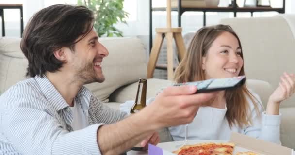 Couple profiter de la nourriture et des boissons tout en regardant la télévision à la maison — Video