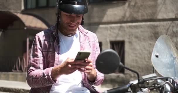 Mannen sitter på scooter och använder mobiltelefon — Stockvideo