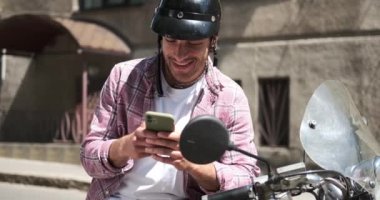 Scooter 'da oturan ve cep telefonu kullanarak selfie çeken bir adam.