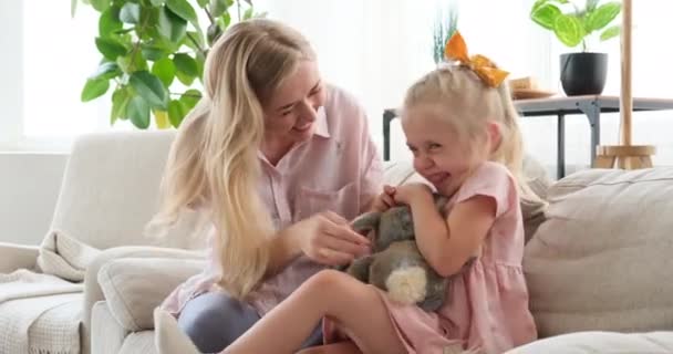 Juguetona madre cosquillas hija en el sofá en casa — Vídeo de stock