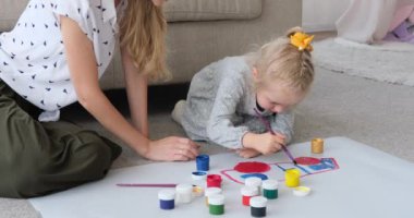 Anne ve kızı evde kağıt çarşaf üzerinde resim yapıyorlar.