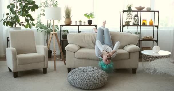 Hipster femeie folosind telefonul mobil culcat cu susul în jos pe canapea la domiciliu — Videoclip de stoc