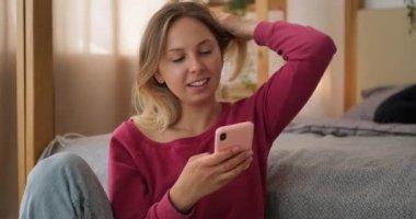 Evde, yatak odasında cep telefonu kullanan sürpriz bir kadın.