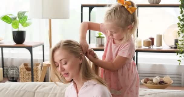 Klein meisje maken haar vlecht van haar moeder thuis — Stockvideo