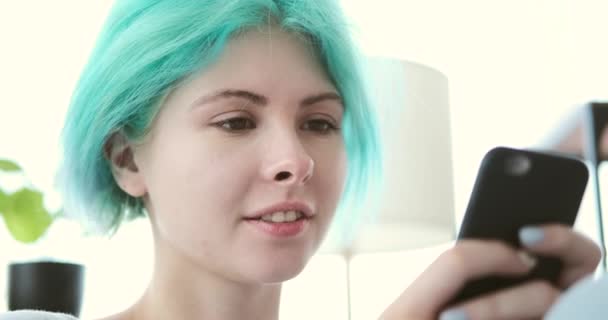 Kobieta z miętowym kolorem włosów za pomocą telefonu komórkowego w domu — Wideo stockowe