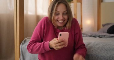 Kadın, evdeki cep telefonunu kullanarak iyi haberler almaktan memnun.