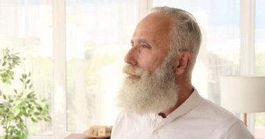 Kıdemli adam evde gülümsüyor.