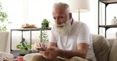 Yaşlı adam evde cep telefonu kullanırken birini çağırıyor.