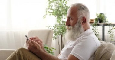 Yaşlı adam evdeki cep telefonunu kullanarak mesaj atıyor.