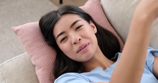 Счастливая женщина отдыхает на диване дома — стоковое видео