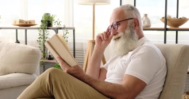 Oude man die thuis een boek leest — Stockvideo