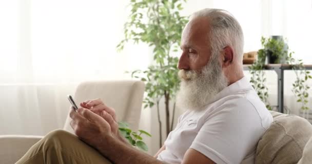 Yaşlı adam evdeki cep telefonunu kullanarak mesaj atıyor. — Stok video