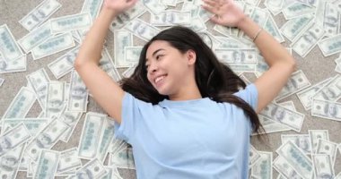 Dağınık dolarların üzerine uzanmış bir kadın