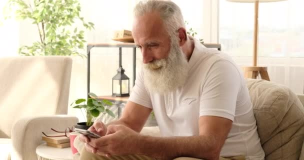 Öregember SMS-ezés mobiltelefonnal otthon — Stock videók