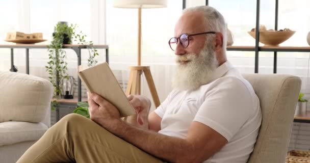 Yaşlı adam evde kitap okuyor. — Stok video