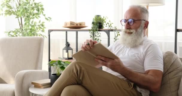 Yaşlı adam bir kitap okurken kalemle işaretliyor. — Stok video