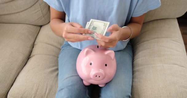 Жінка вставляє гроші в скарбничку вдома — стокове відео