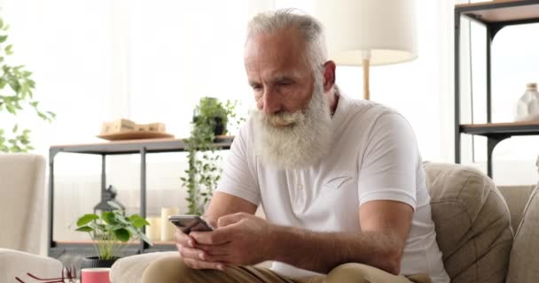 Mensajería de texto de anciano usando teléfono móvil en casa — Vídeos de Stock