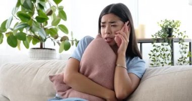 Evde cep telefonuyla konuşan üzgün bir kadın.