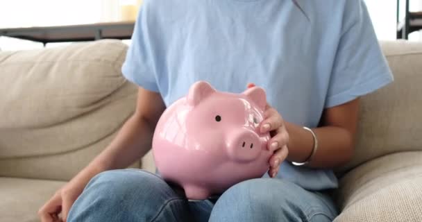 Kadın evdeki domuz kumbarasına para sokuyor. — Stok video