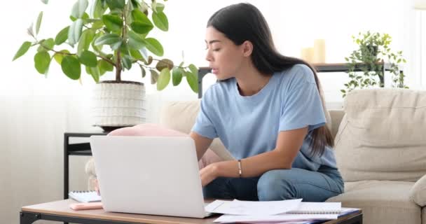 Mujer analizando documentos y usando laptop en casa — Vídeos de Stock