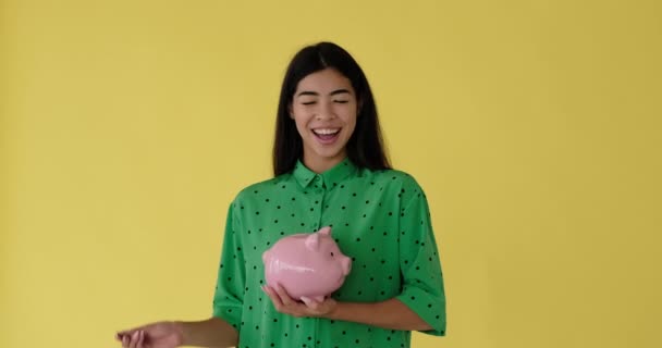 Smiling woman inserting coin into piggy bank — Stock Video